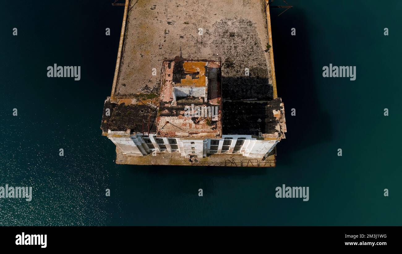 Aerial view of an old rusty pier and blue turquoise water. Shot. Abandoned old concrete pier and the sea water Stock Photo