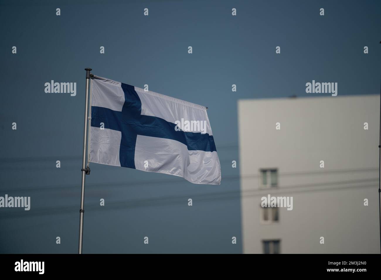 Hoisted Finnish flag on blue sky. Stock Photo