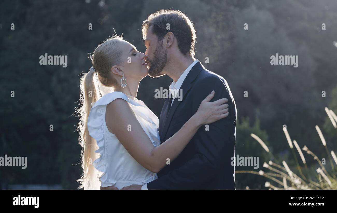 Newlyweds kiss in nature with sunlight. Action. Beautiful couple of ...