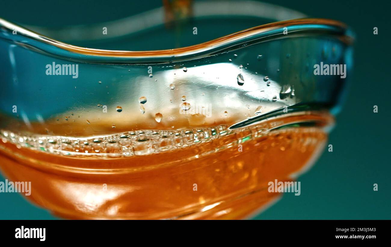 A bright glass with cognac. Stock clip.A large mug in which expensive whiskey is poured. High quality 4k footage Stock Photo