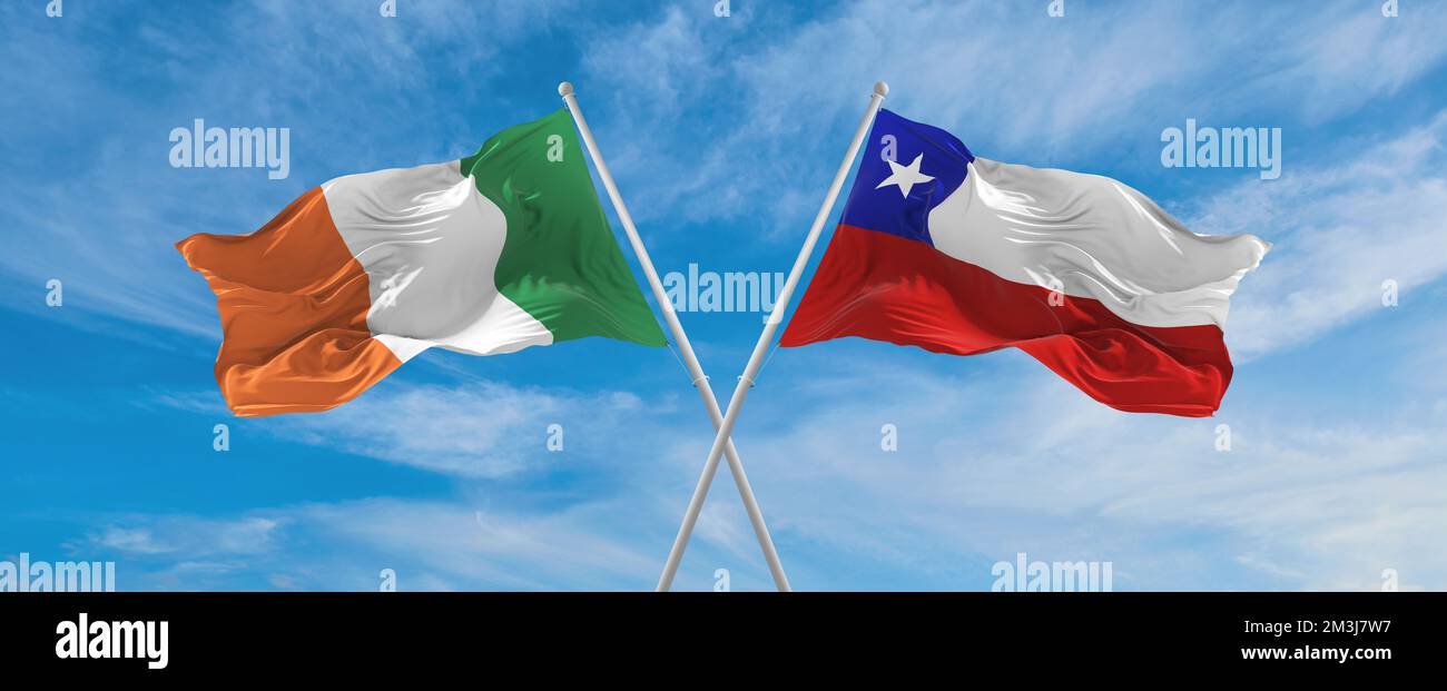two crossed flags Chile and Ireland waving in wind at cloudy sky ...