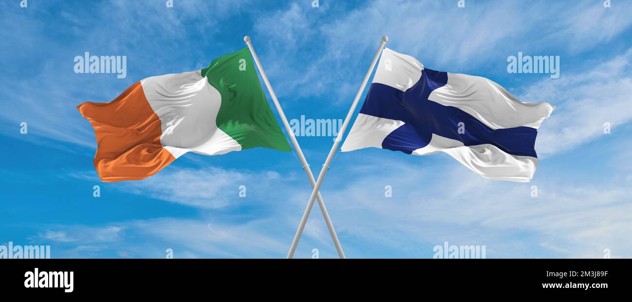 two crossed flags Finland and Ireland waving in wind at cloudy sky ...