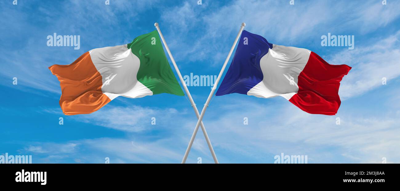 two crossed flags France and Ireland waving in wind at cloudy sky ...