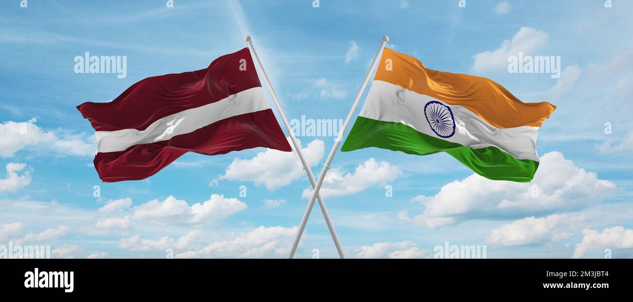 two crossed flags India and Latvia waving in wind at cloudy sky ...
