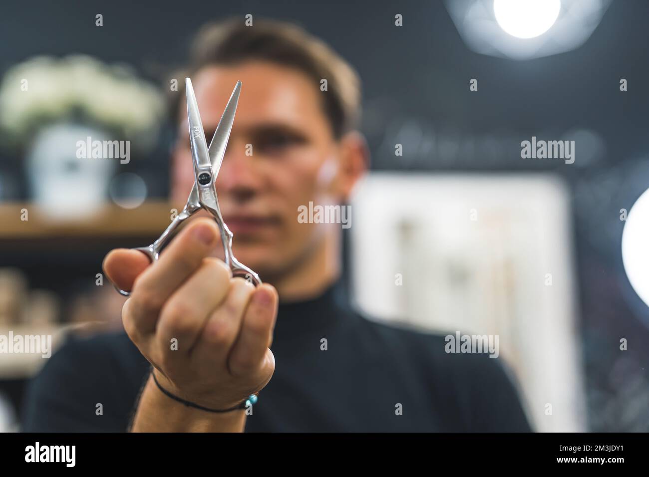 Blurred hairdresser man holding scissors in front of his face. High quality photo Stock Photo