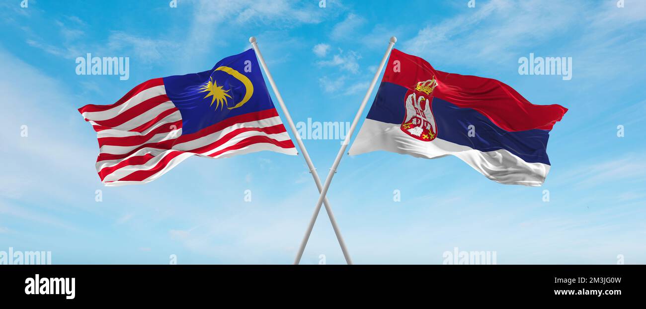 two crossed flags Serbia and Malaysia waving in wind at cloudy sky ...