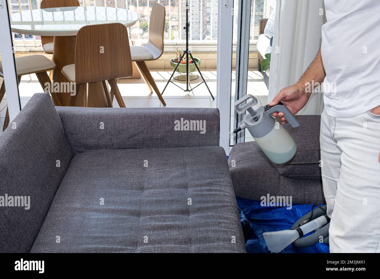 Man spraying a liquid to clean gray sofa cushions Stock Photo Alamy
