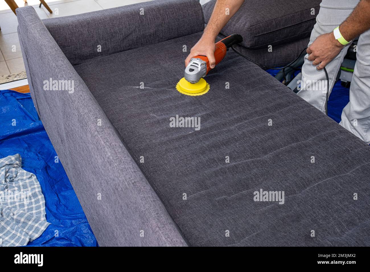 Man using an electric polisher brush to clean sofa cushions Stock Photo