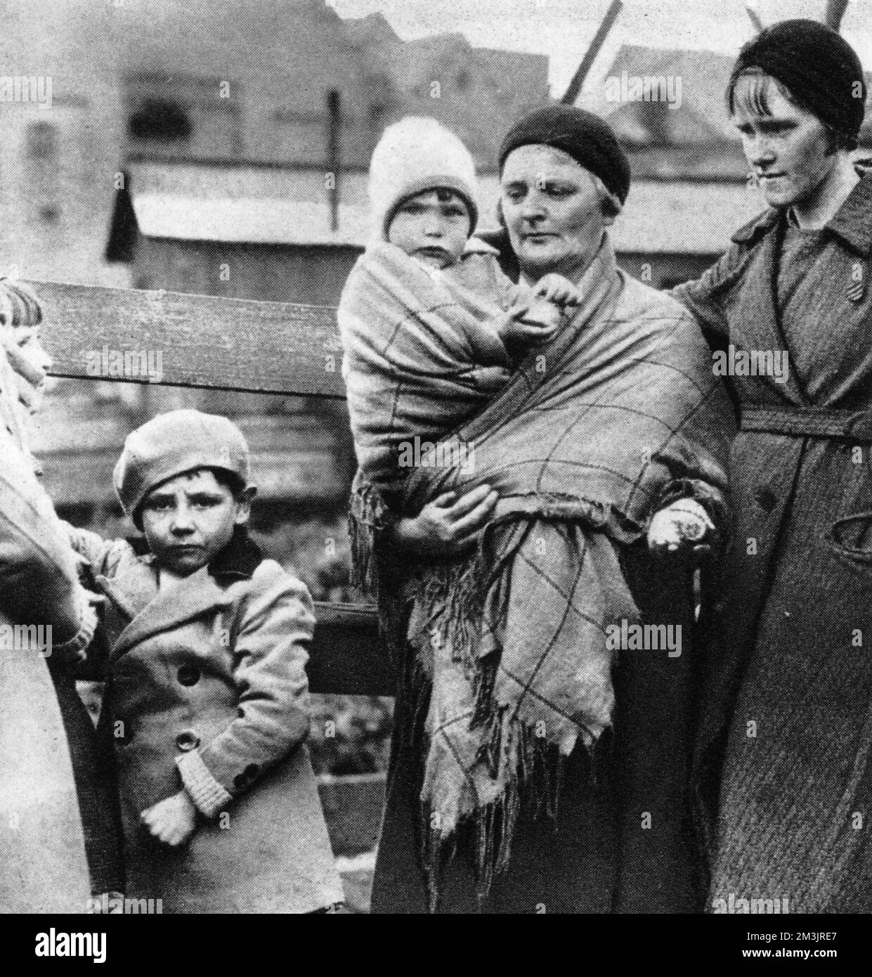 A family wait by the pithead after the great explosion at Gresford colliery in Wales. Over 260 miners lost their lives as a result of raging fires in the pits, orphaning nearly 800 children.     Date:  1934 Stock Photo
