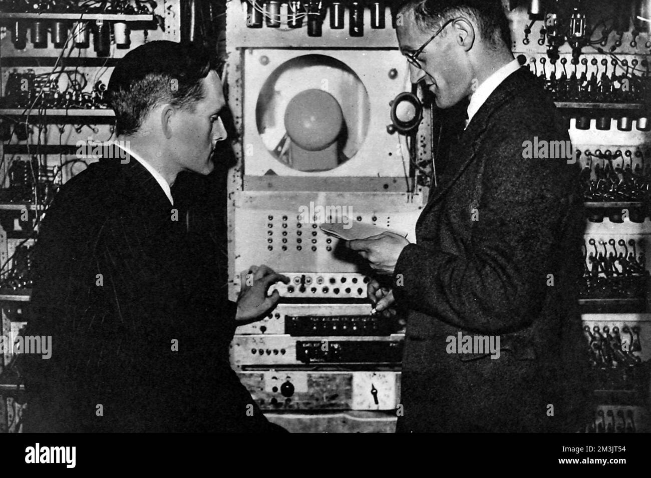The control panel of the automatic sequence-controlled calculating machine at Manchester University; showing the monitor cathode-ray tube with Dr. T. Kilburn (left) and Professor F. C. Williams (right), inventor of the memory storage system. Williams became Professor Electrical Engineering at Manchester in 1946 is chiefly known for his development of the Williams tube, the first successful electrostatic random access memory for the digital computer. This enabled him, along with Kilburn, to operate the world's first stored-program computer in June 1948.  1949 Stock Photo