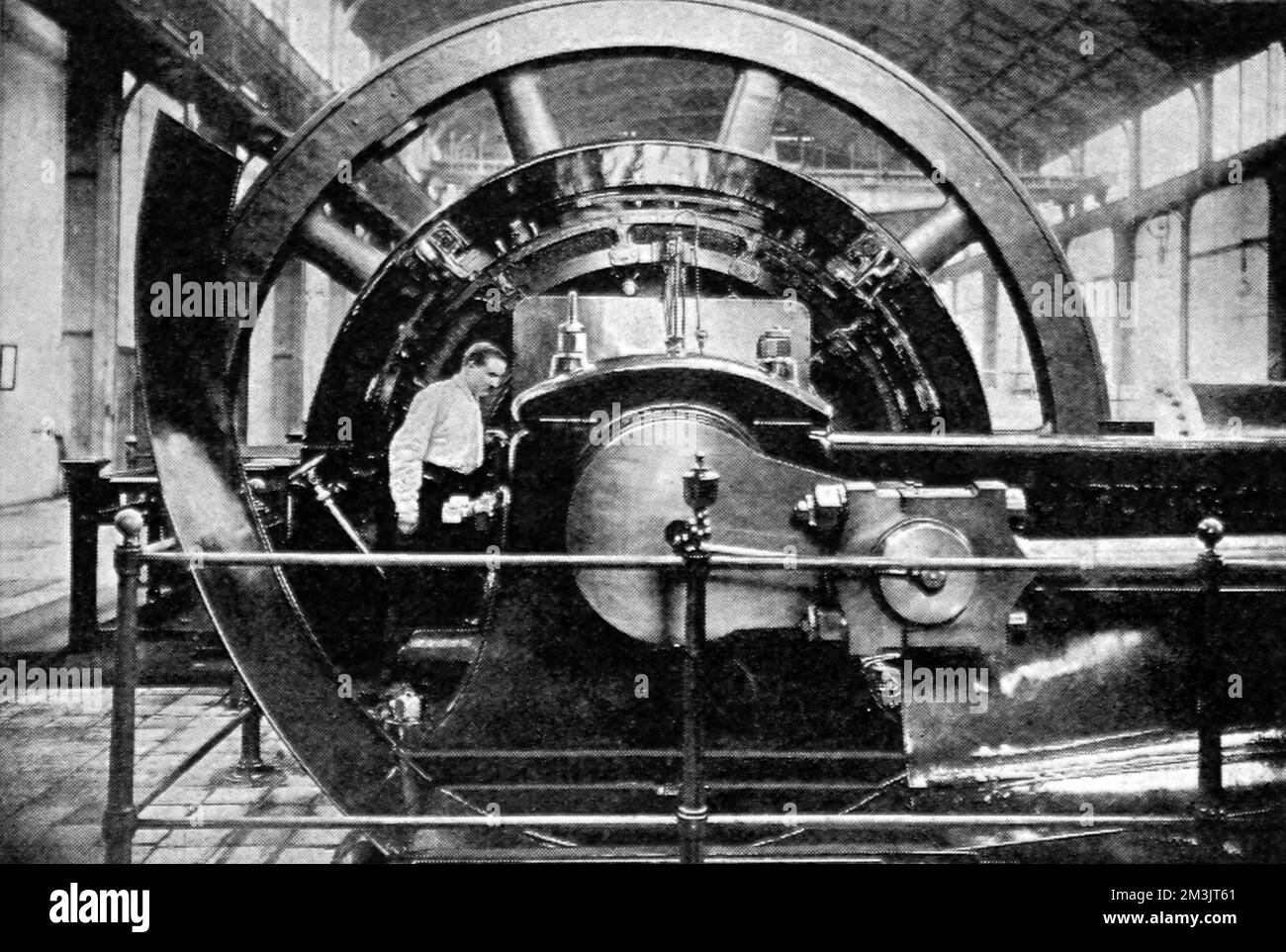 A huge fly-wheel dynamo at St. Denis station, used to light Paris. There were eight dynamos at the St. Denis station, producing a high tension current of 2250 volts and 210 amps. The fly-wheel was twenty-one feet in diameter.     Date: 1908 Stock Photo