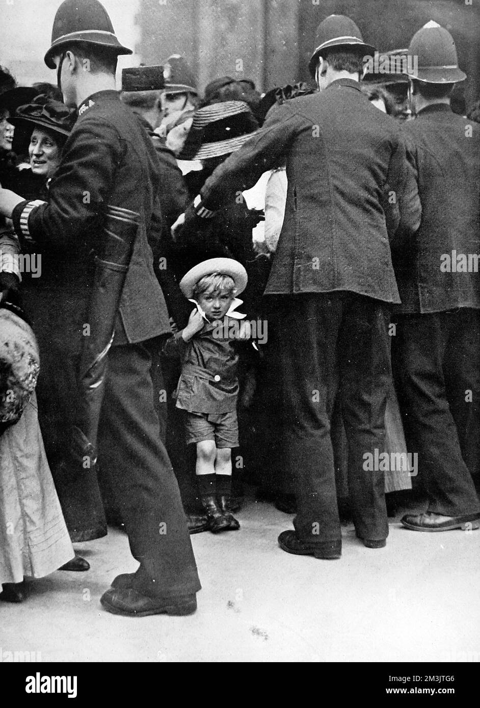 A photographic study entitled, ' I want to go home, mother.' A small child pictured at the edge of a large crowd being held back by the police.  1911 Stock Photo