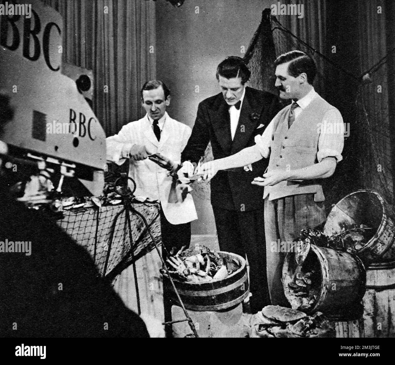 Mr Cunningham of Cunningham's, Mayfair standing before the television camera during a 'Picture Page' broadcast with Leslie Mitchell. The 'Picture Page' was a favourite of British television audiences, with 262 editions going out before the war.     Date: 1949 Stock Photo