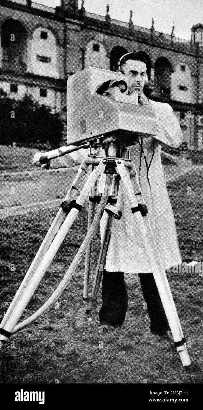 The E.M.I camera recording a scene. The E.M.I camera was one of the methods that the B.B.C experimented with for its live broadcasts. The camera is seen here in the grounds of Alexandra Palace, with the recording conveyed by cable to the television transmitter.  1936 Stock Photo