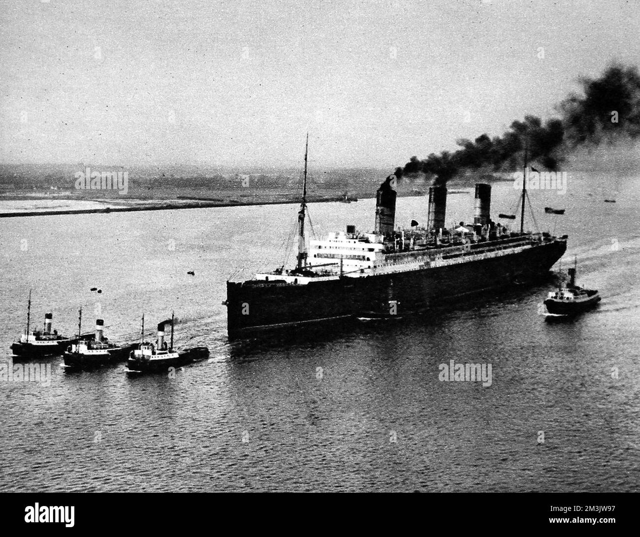 Photograph of the Cunard Liner 'Berengaria' heading out of Southampton, with tugs, to head to Jarrow to be broken up, December 1938. 'Berengaria' was built at the AG Vulcan shipyard, Hamburg, in 1913 and launched as 'Imperator' for the Hamburg-Amerika Line.   She was laid up, unused, during the First World War then given to Britain as war reparations at the ceasation of violence. Cunard bought her shortly thereafter and used her on the Southampton, Cherbourg, New York route from 1921 until 1938. Unfortunately she lost her Passenger Certificate in 1938 due to the senility of her electrica Stock Photo
