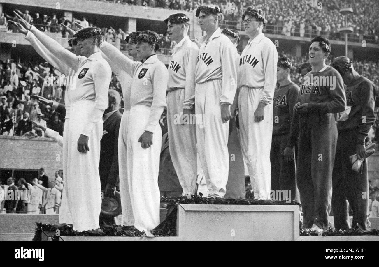 The British 4 x 400m relay team taking gold at the 1936 Berlin Olympic Games, seen here on the podium along with the German and American teams. All athletes were laurel leaves on their heads while the German team make a Nazi salute. The Olympic Games had been handed to Germany prior to the Nazis coming to power, and Hitler used the opportunity to display German military might and the alleged superiority of the 'Master Race', a theory which was thoroughly disproved by African American athlete Jesse Owens who went on to win 4 gold medals.     Date: 1936 Stock Photo
