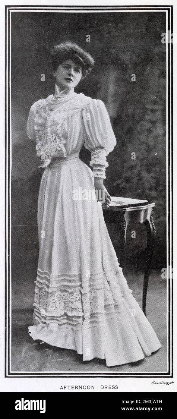 Woman wearing an afternoon dress, made of white voile over straw coloured silk. The bodice and skirt were trimmed with Irish lace, finished with a belt of Liberty satin. Stock Photo