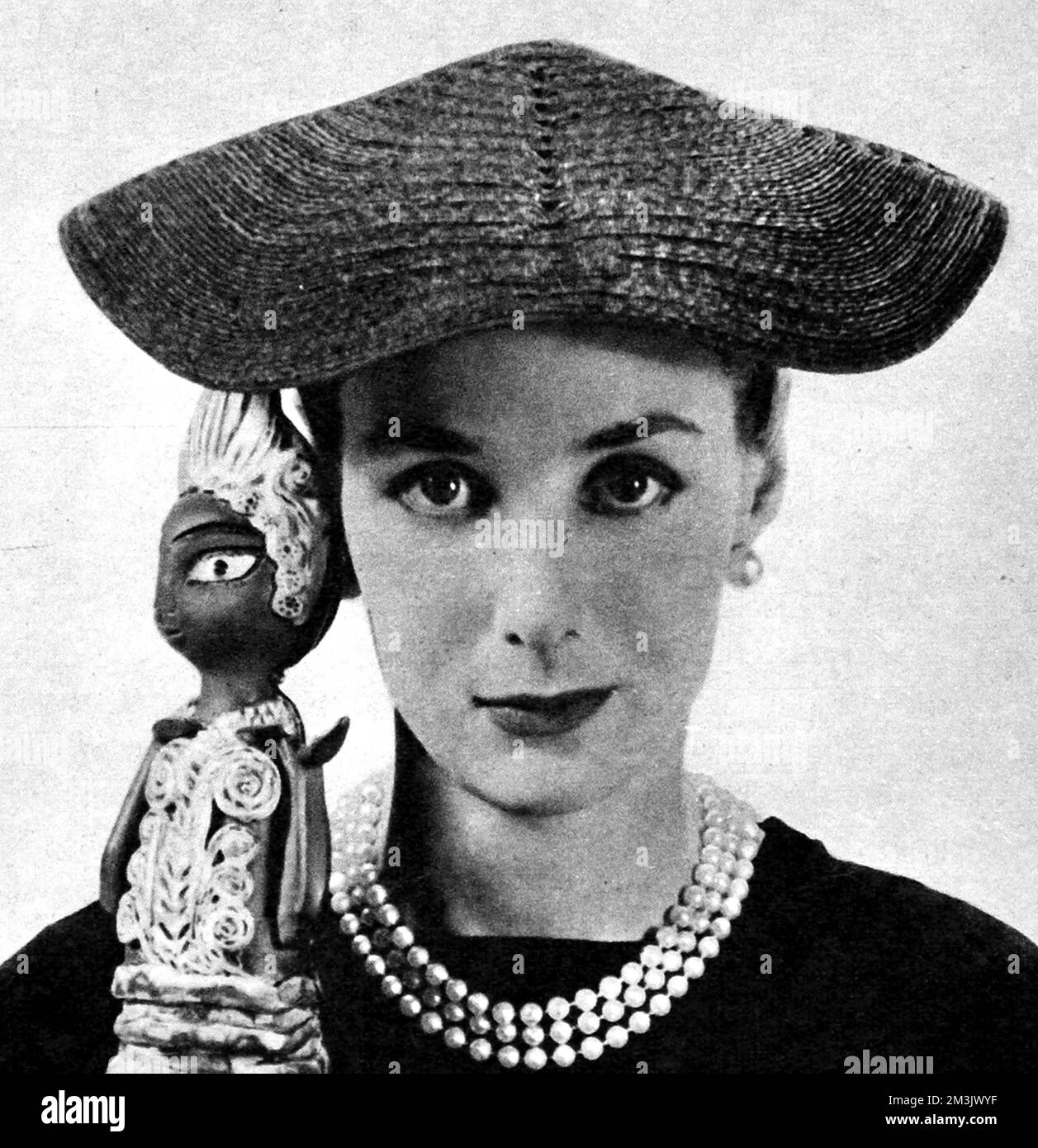 Green pedal straw hat, which framed the face with its curved brim, 1955