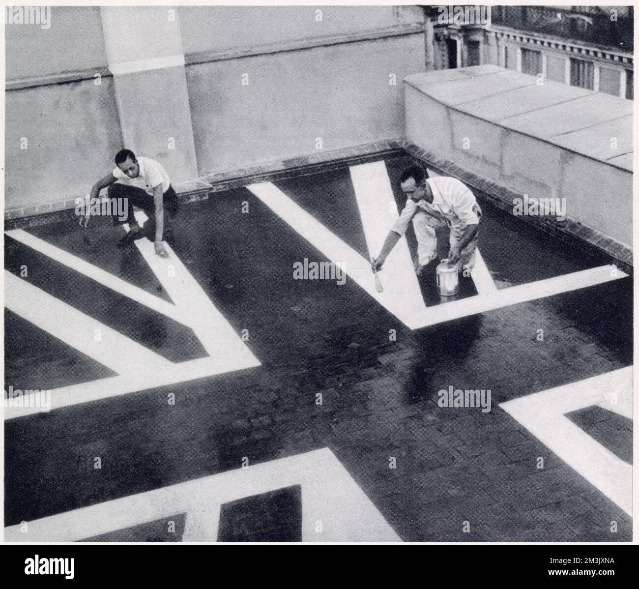 British Embassy staff painting their roof the colours of the Union 'Jack', in an attempt to signify their neutral presence to Nationalist bombers during the Spanish Civil War, Madrid, 1936.   The Spanish Civil War, which started in 1936 between the Republican Government and the Nationalist Rebels, featured some of the earliest heavy bombing of civilian areas. Stock Photo