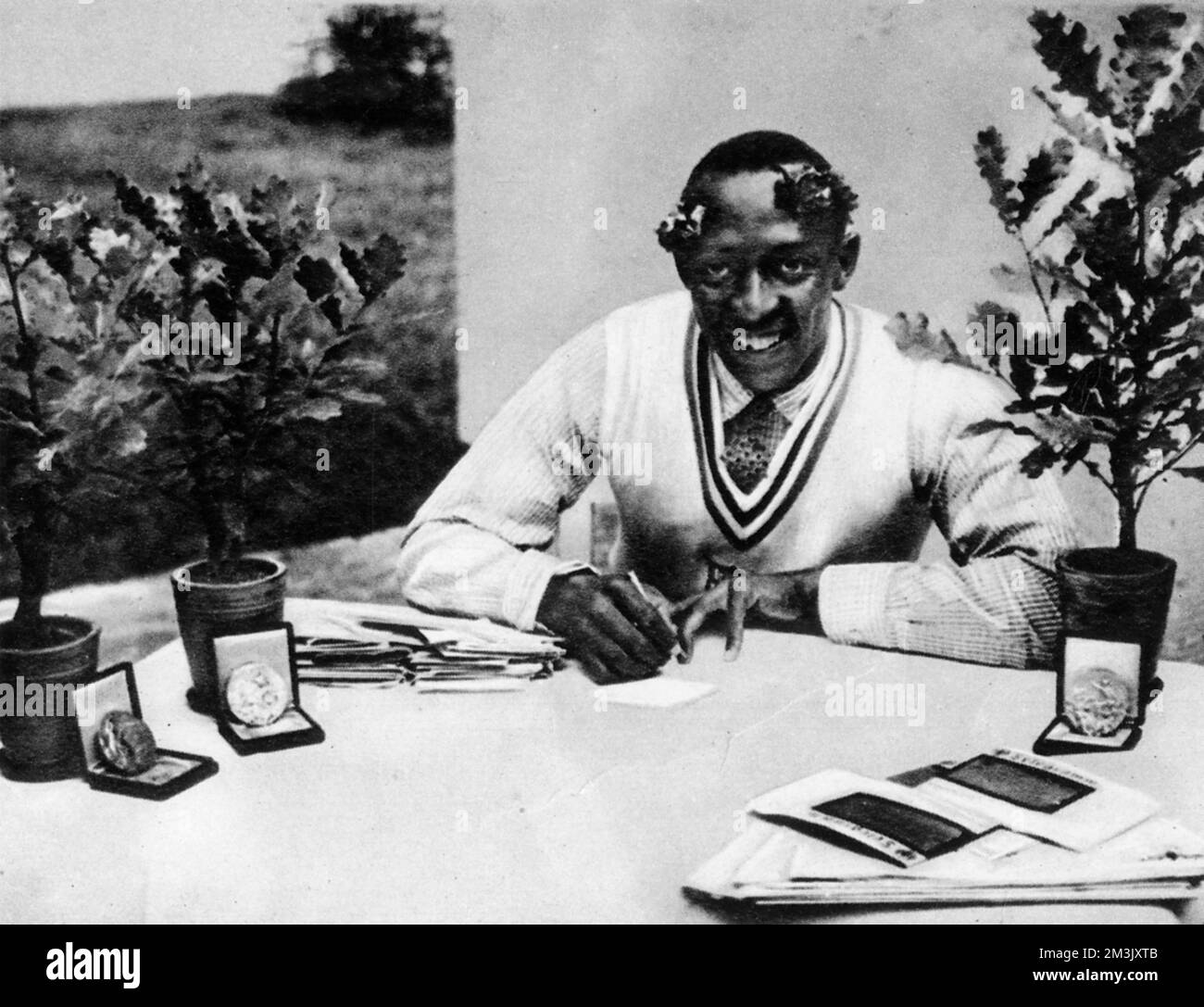 Jesse James Cleveland Owens (1913 - 1980), US athlete, pictured with his Olympic oak-trees and medals.  Owens won four gold medals at the the 1936 Berlin Olympics - the 100 metres, the 200 metres, the long jump and the 4x100 metres relay.  1936 Stock Photo