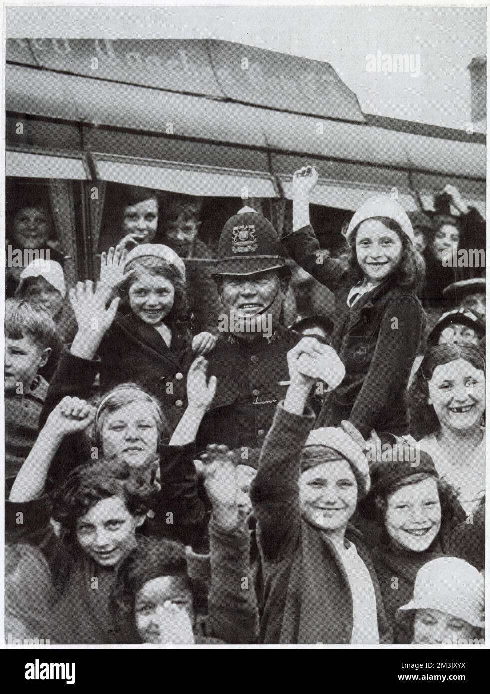 A policeman surrounded by children from the East End of London, prior to their setting off on a day trip to the countryside, at West India Docks, London, 1936. The day trip had been organised and paid for by policemen of the Port of London Authority. Stock Photo