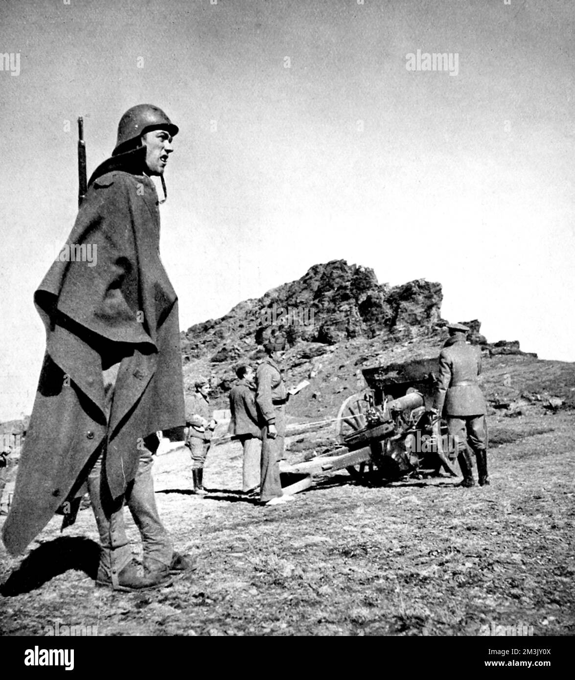 Photograph showing an infantryman (left foreground) and an artillery