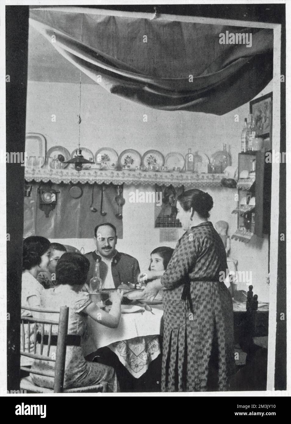 A Civil Guardsman having dinner with his family in their private rooms at a Civil Guard Barracks, Spain, 1936.   The Civil Guard were a cross between a military unit and a police force, who worked to maintain peace and order in Spain in both times of war and peace. The Civil Guard took an active role in the Spanish Civil War, with guardsmen serving both the Republicans and the Nationalists. Stock Photo