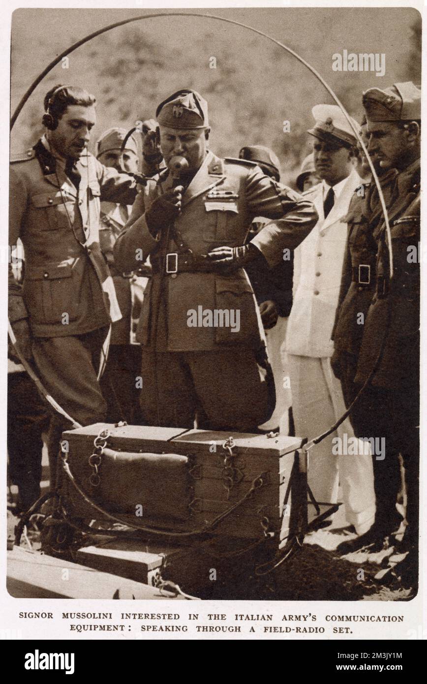 Photograph showing Benito Mussolini (1883 - 1945), the Italian dictator, testing a radio set during the Italian Army manoevres of August 1936.   On 30th August that year Mussolini broadcast a speech in which he claimed that the Italian army could mobilise 8 million men, with only a few hours notice. Stock Photo