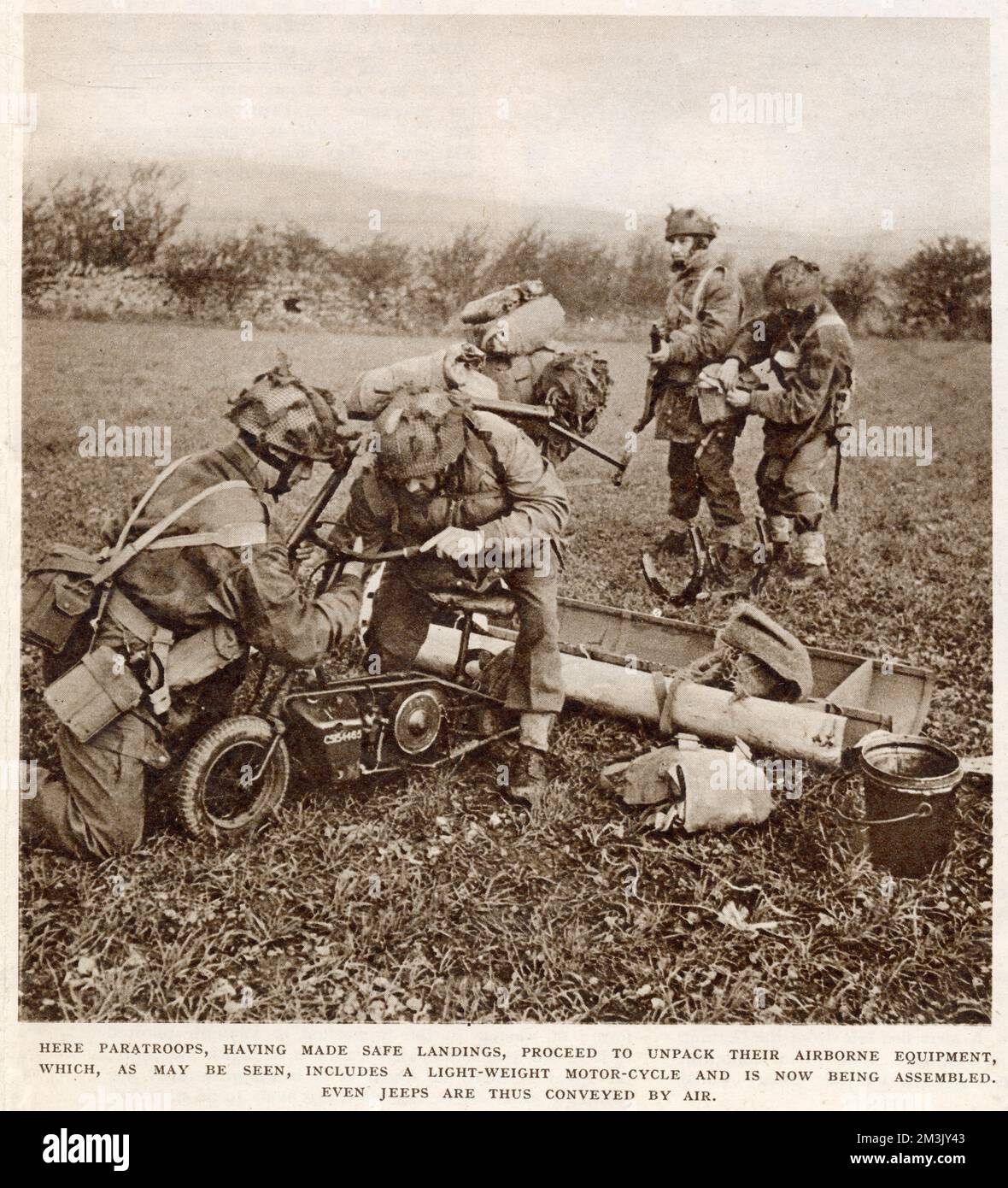 A group of British paratroops readying themselves after landing, during an exercise taking place in England in 1944.   The two men in the foreground are seen assembling a lightweight motorcycle, whilst those in the background are packing their gear. Stock Photo