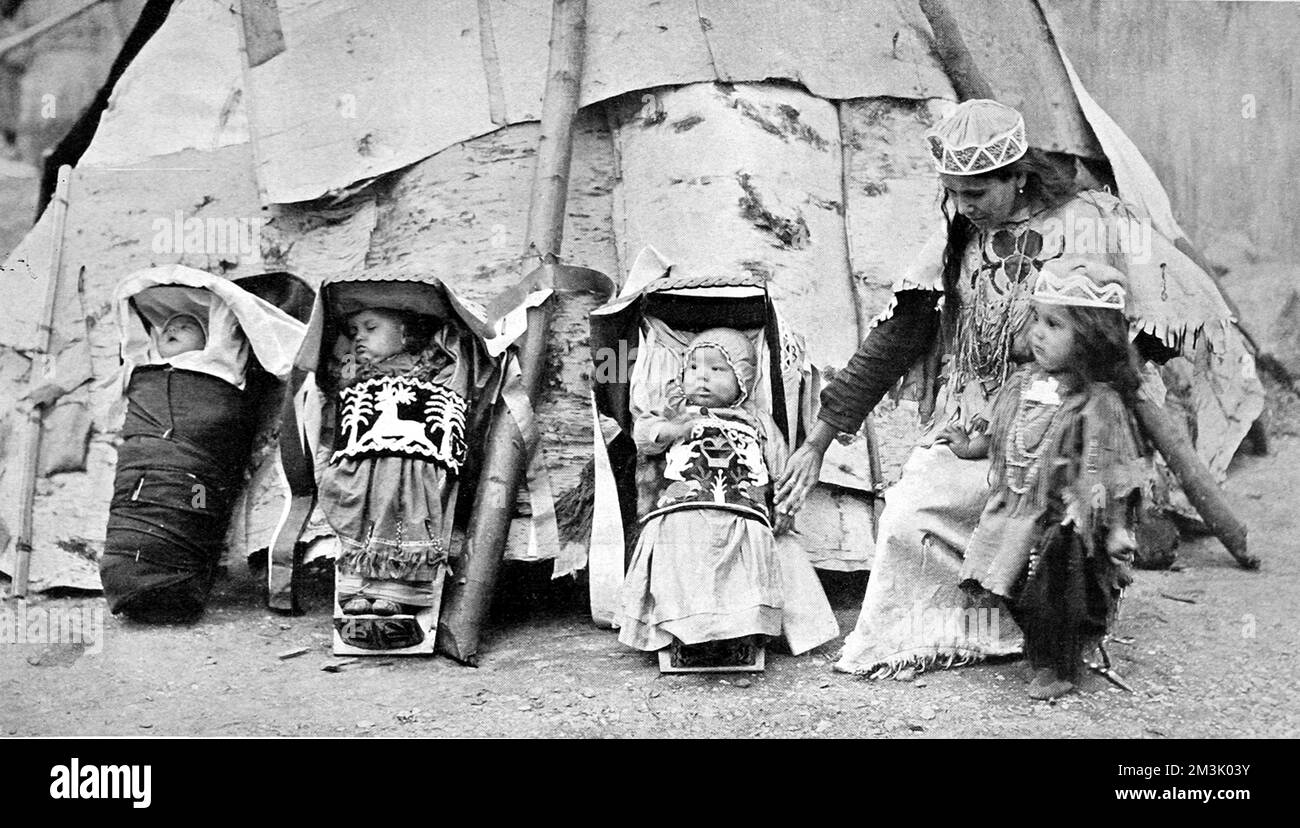 Red Indian babies, or papooses at Earl's Court. Three Red Indian babies outside a teepee, with an Indian child and woman.     Date: 1905 Stock Photo