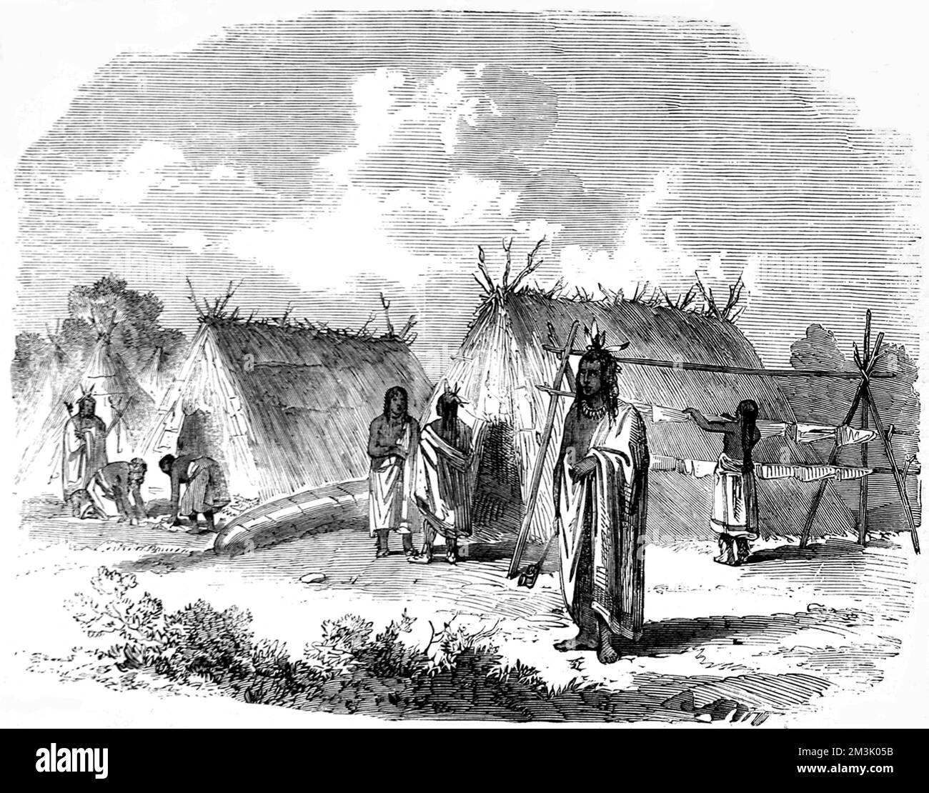 Ojibway Indians, wearing wraps and feathers in their hair, with thatch triangular huts in the background and what looks like a washing line. The Canadian government funded several expeditions to chart the Red River area in the late 1850's.     Date: 1858 Stock Photo
