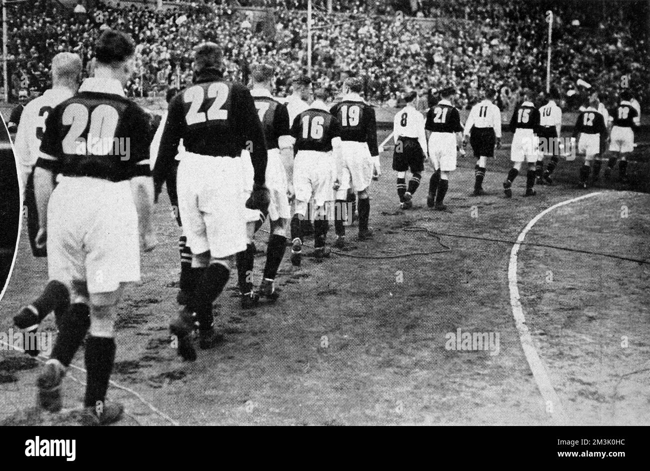 The Everton (light shirts) and Manchester City (dark shirts) teams walking onto the pitch at Wembley Stadium, prior to the start of the F.A. Cup Final of 1933. Everton won the game 1-0, thanks to a goal from Dixie Dean.  This was one of the first occasions on which footballers wore numbers on the back of their shirts. The reason for this innovation was to help the BBC radio commentators and their listeners follow the action. As can be seen, Everton took the numbers 1 to 11 and Manchester City took 12 to 22.     Date: 1933 Stock Photo