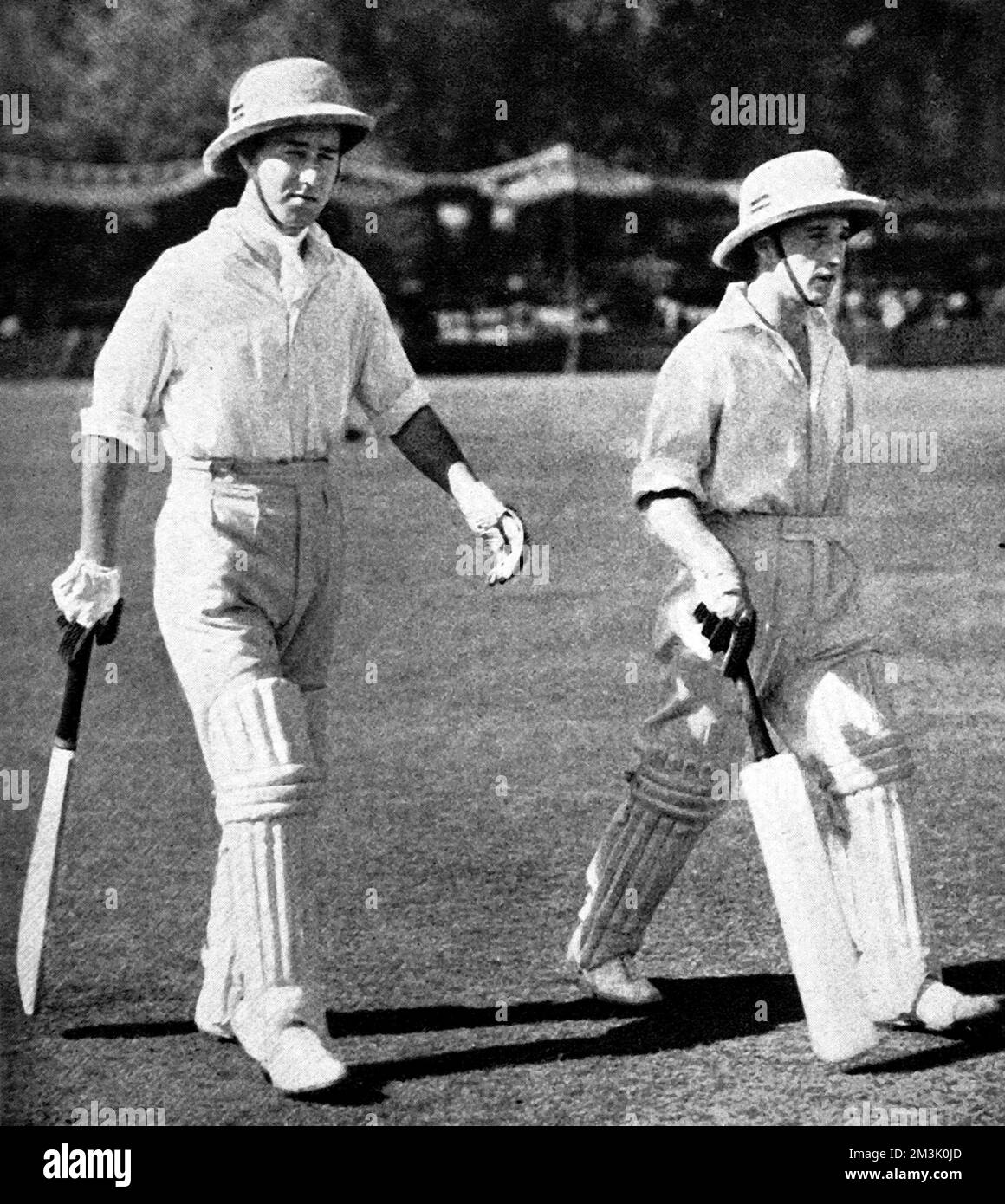 Photograph of W. Edrich and N.W.D. Yardley walking out to open the innings for the Lord Tennyson XI, in the match against an All-India XI, held at Lahore, 1937.  As can be seen, pith helmets were the order of the day during this unofficial 'Test' series.     Date: 1937 Stock Photo