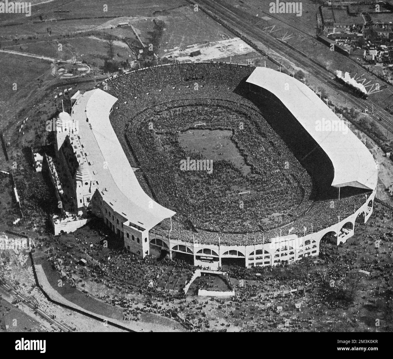 Aerial photograph of Wembley Stadium before the start of the 1923 F.A. Cup Final between Bolton Wanderers and West Ham United. This was the first Cup Final held at the then brand-new Wembley Stadium, which had been built in 300 days at a cost of ??750,000.  Before the match began a crowd of about 100,000 (most without a ticket) stormed through the gates and into the stadium. This meant that there was approximately 200,000 people in a ground designed for 127,000.   The photograph shows the scene as the spectators moved onto the pitch, due to the pressure of people behind them. The match started Stock Photo