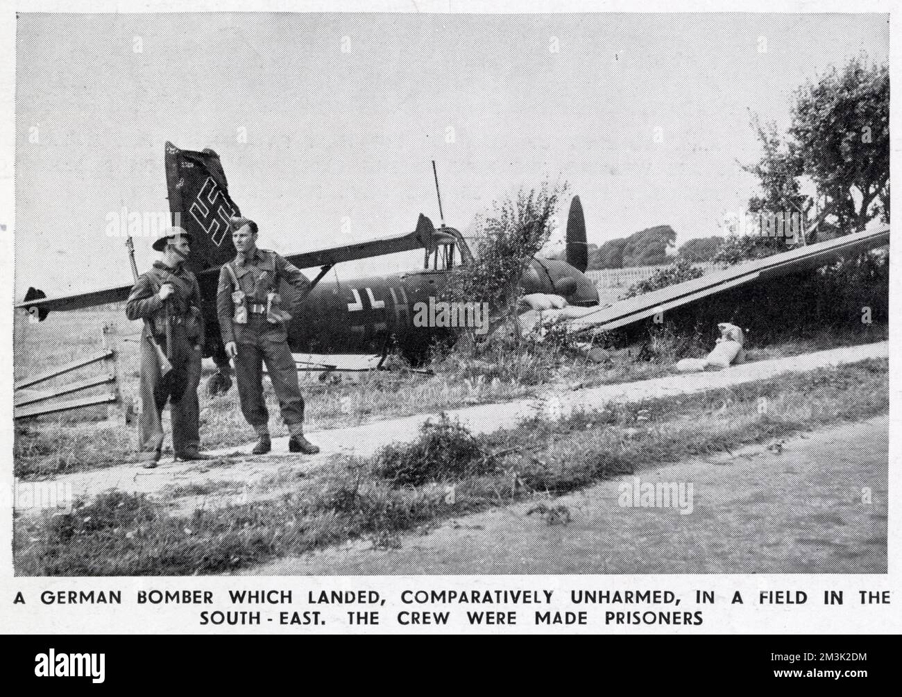 A crashed German Junkers Ju-87 dive-bomber, also known as a 'Stuka', somewhere in South East England during the summer of 1940. Two British soldiers are seen guarding the crashed airplane. Stock Photo