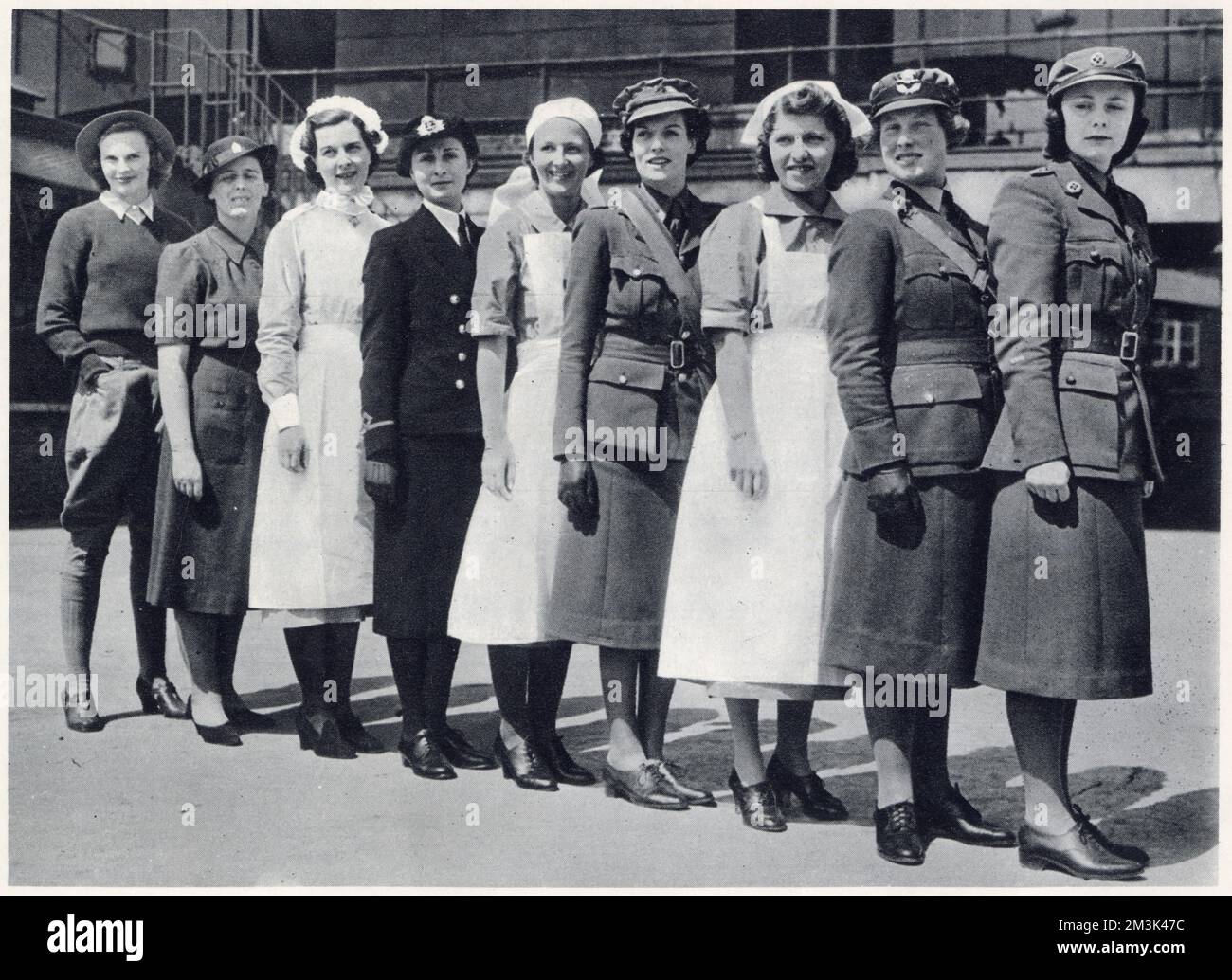 Nine female employees of Harrods in their war-time uniforms, each woman working for a different 'service'.   From left to right: Woman's Land Army, Women's Voluntary Services, St. John Ambulance Brigade, Women's Royal Emergency Naval Service, Red Cross, Auxiliary Territorial Service, Civil Nursing Reserve, Women's Auxiliary Air Force and the Mechanised Transport Corps. Stock Photo