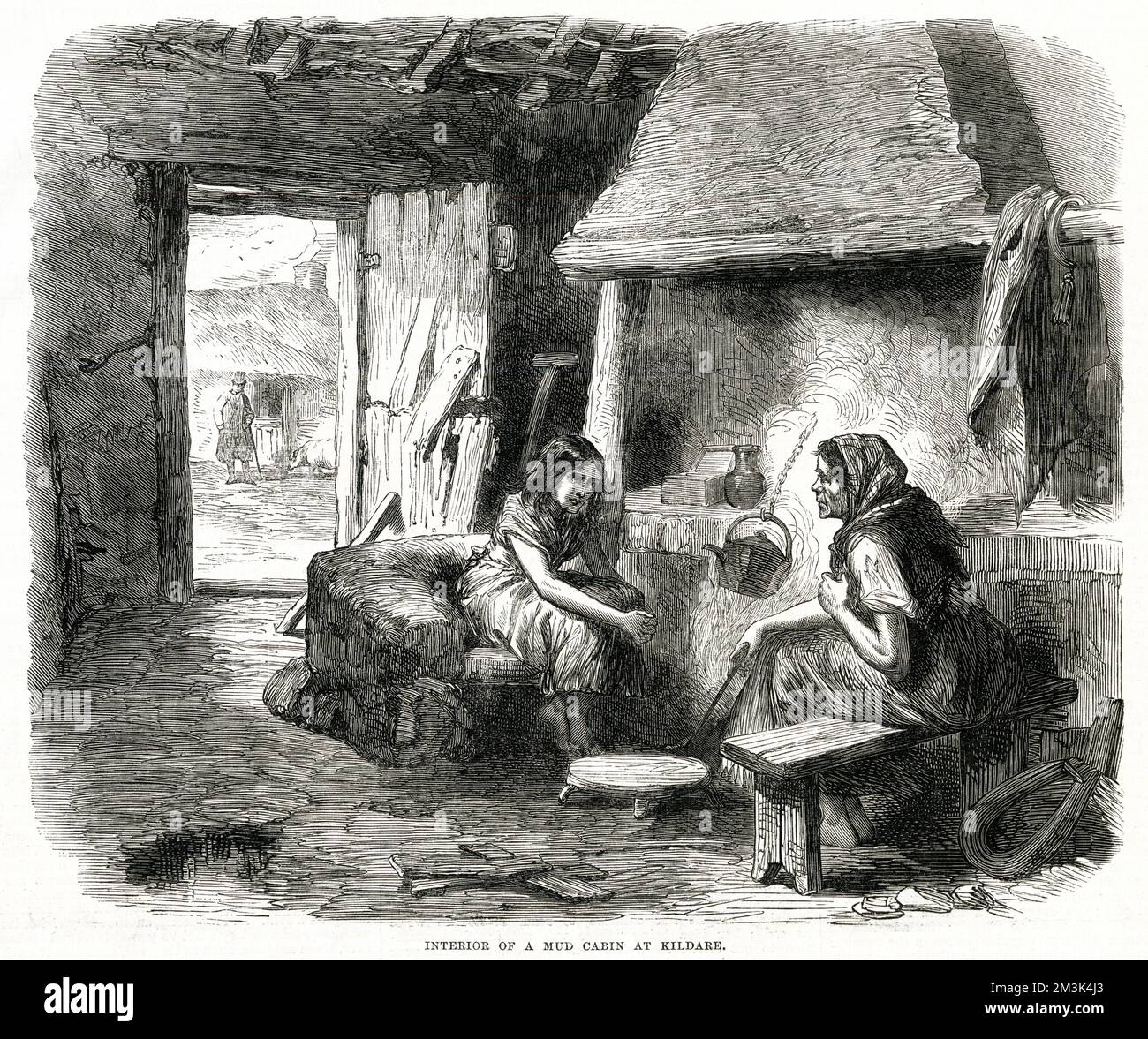 A woman and young girl indoors in a mud cabin in Kildare. They sit next to the fire over which a kettle hangs on a chain. This is a poor ramshackle dwelling with the door nearly falling apart and a view of a man and a pig outside.     Date: 1870 Stock Photo