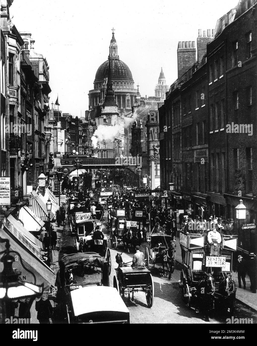 Photograph showing the view east along Fleet Street, towards Ludgate and St. Paul's Cathedral, c.1894.   A large number of horse-drawn carriages can be seen rushing along the street as a steam train heads south towards Blackfriars.     Date: c.1894 Stock Photo