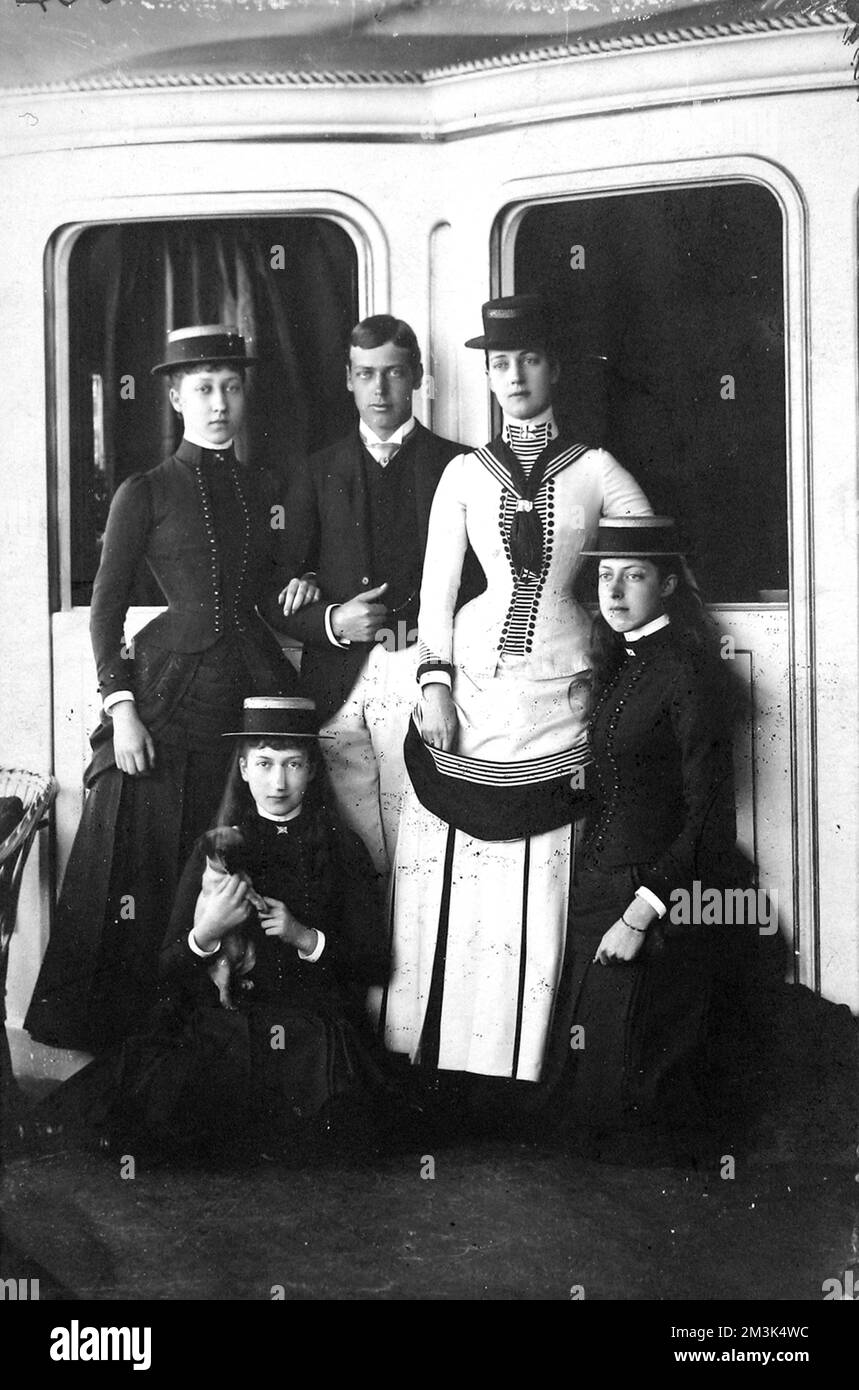 Queen Alexandra with four of her children: from left, Princess Louise, Princess Maud (seated), Prince George (later George V), Queen Alexandra and Princess Victoria. Although not confirmed, the Queen's naval style of dress suggests they are on a boat or ship, possibly the Royal Yacht, 'Britannia'.     Date: 1884 Stock Photo