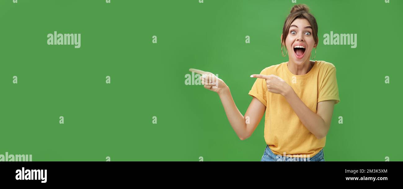 Waist-up shot of enthusiastic and charismatic impressed happy girl laughing and smiling broadly pointing left at funny hilarious thing reacting Stock Photo