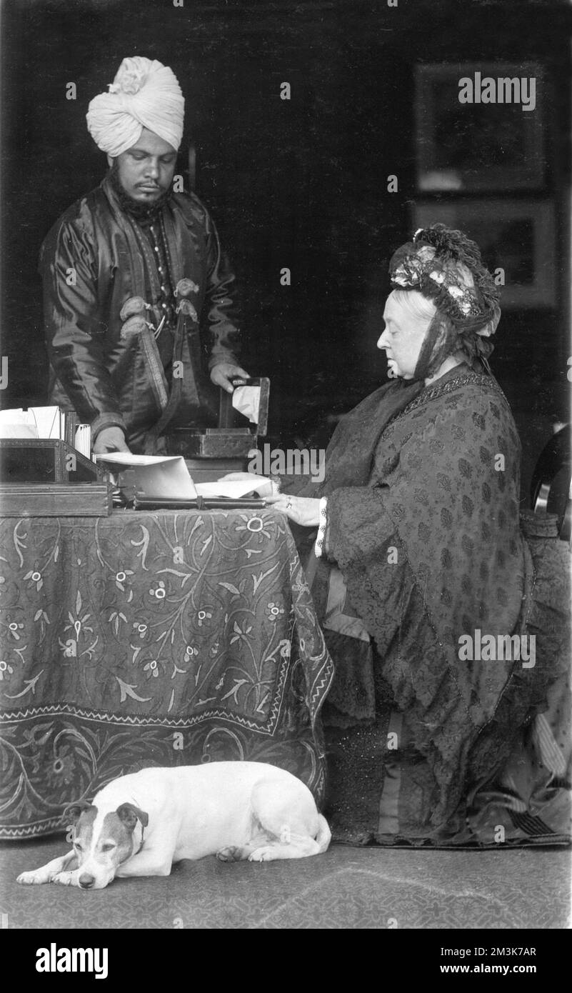 Queen Victoria at her desk, assisted by her servant Abdul Karim, the
