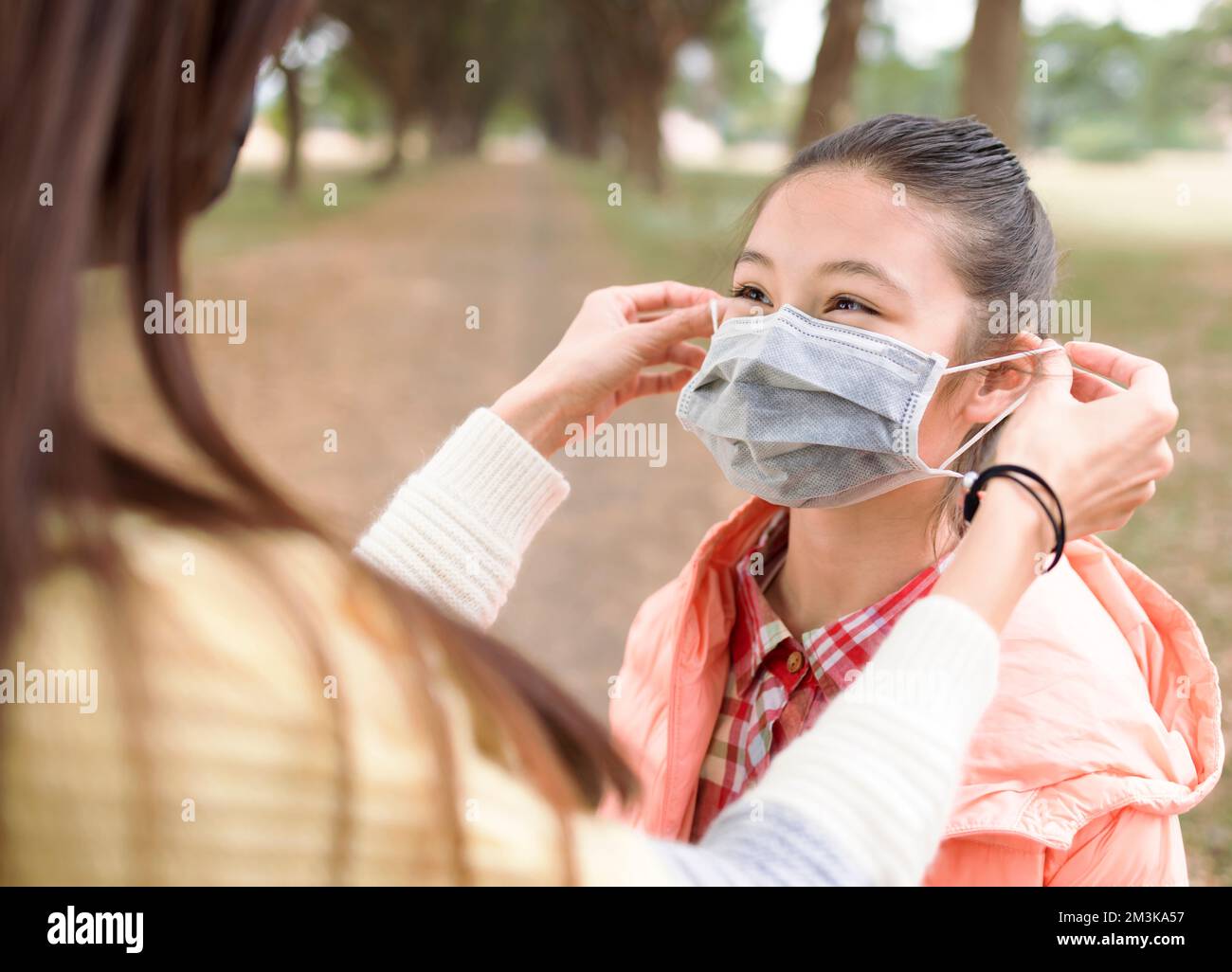 Young mother puts the mask on her daughter to prevent coronavirus. Stock Photo
