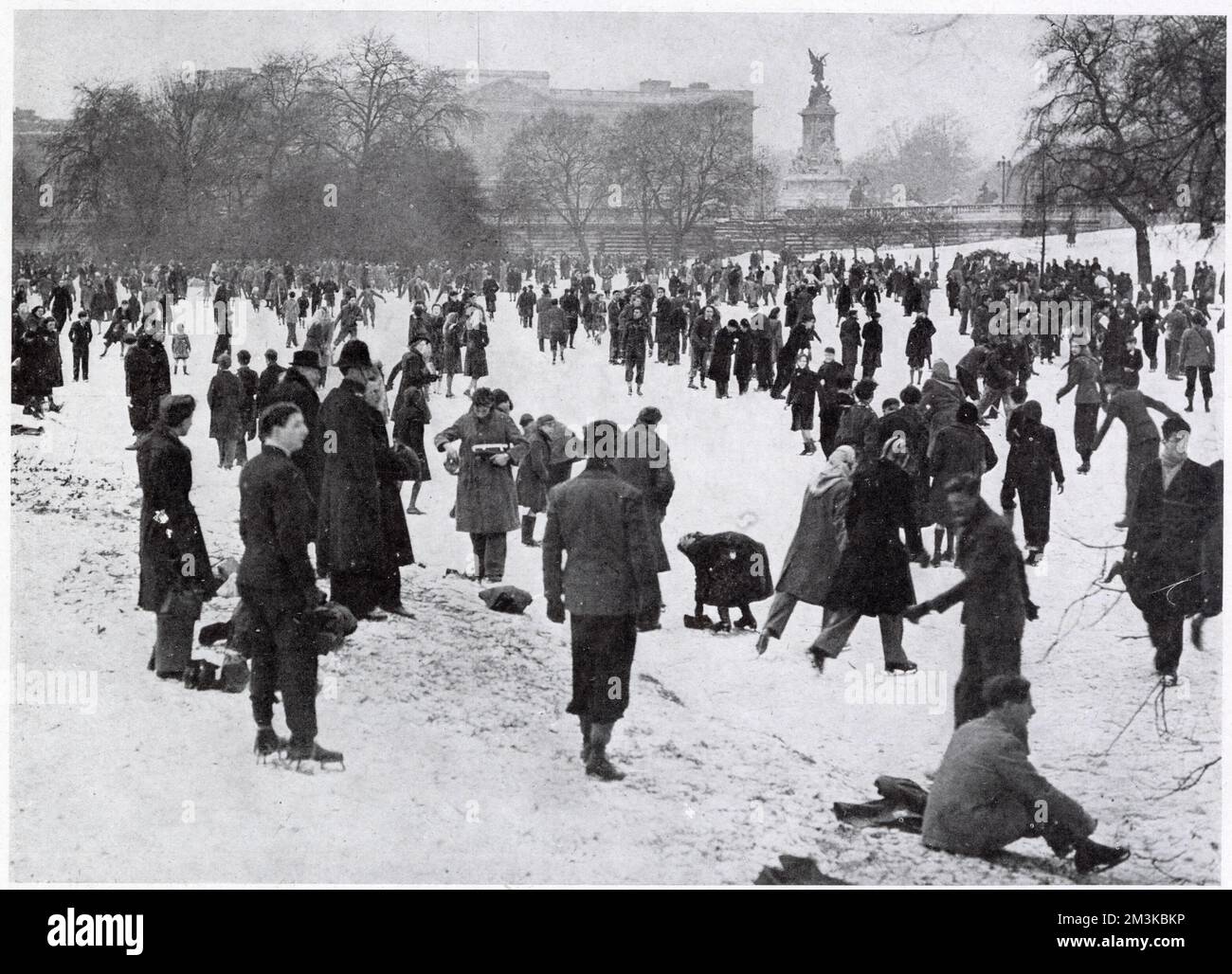 A cheerful crowd disporting on the ice in front of Buckingham Palace.  During one of the coldest winters experienced by Britain, nearly all London lakes were available for skaters, with big crowds turning out on the Serpentine, on the Round Pond, Kensington Gardens, and in Battersea Park. Stock Photo