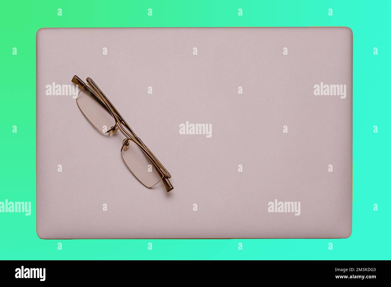 Modern silver closed laptop computer with eyeglasses on top Stock Photo