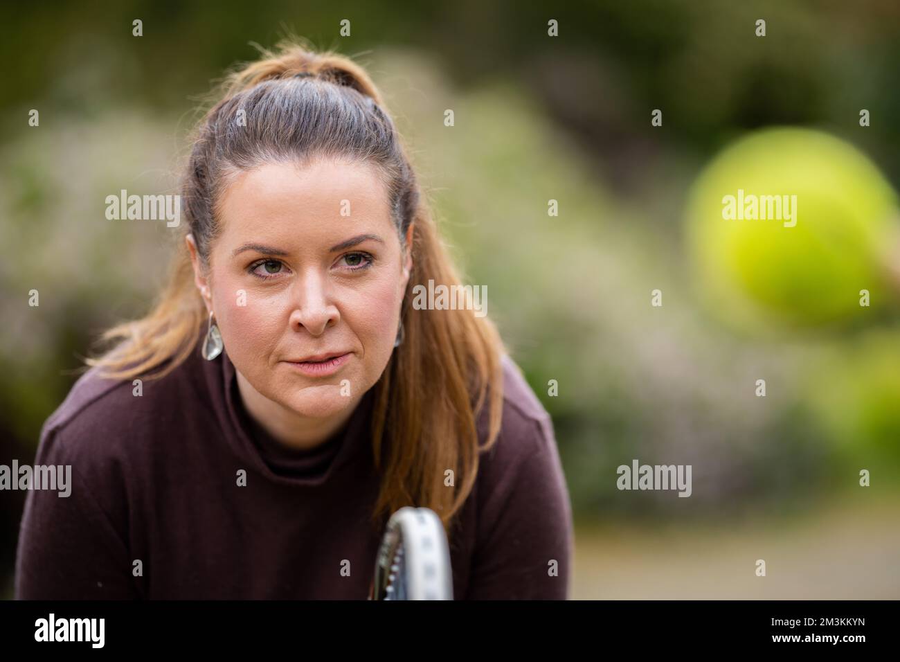 female tennis player practicing forehands and hitting tennis balls on a grass court in england Stock Photo