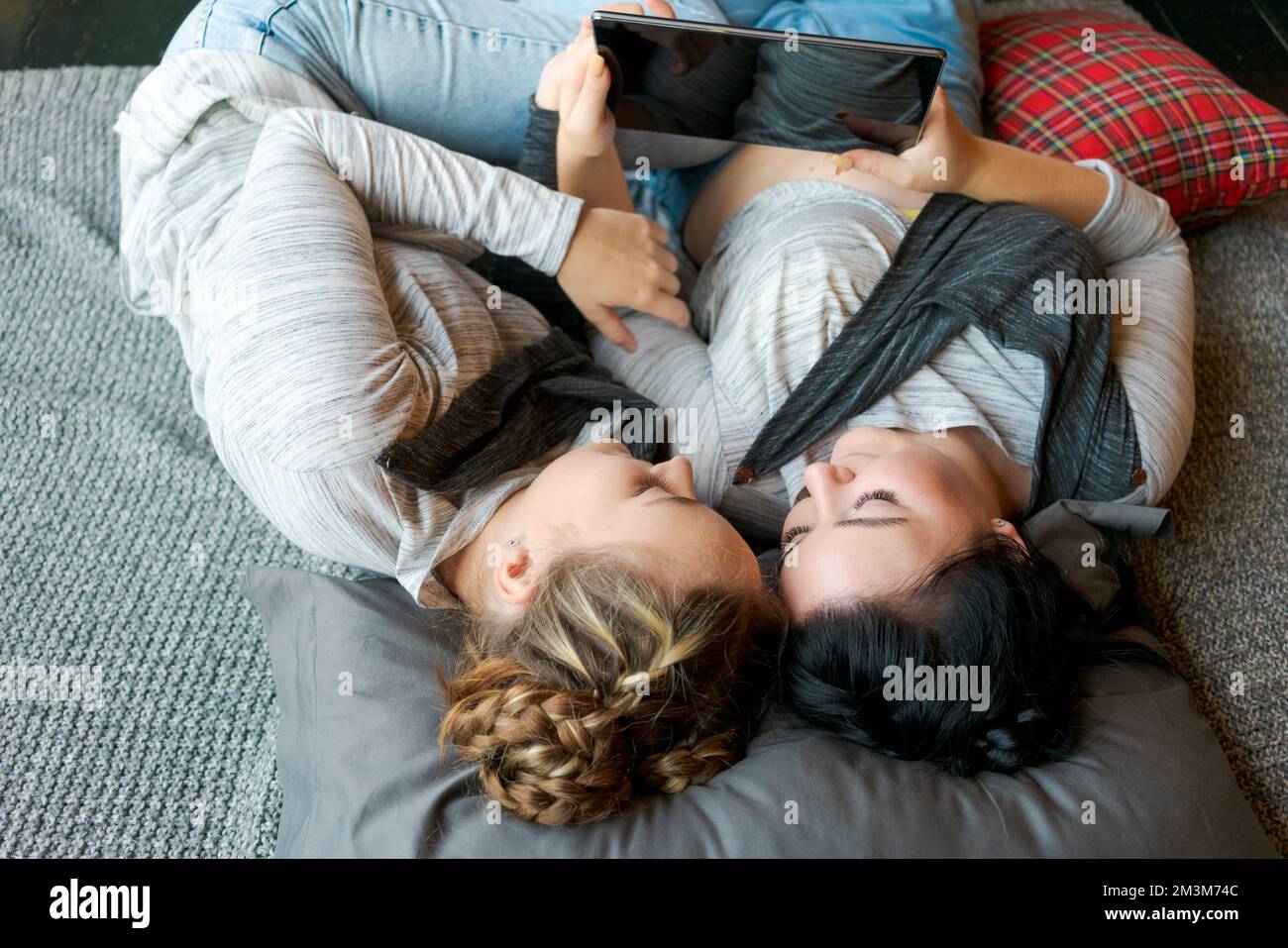 Cheerful caucasian girls sisters lie on floor and watch funny videos on a  digital tablet. Happy relationship, at home enjoying the day off Stock  Photo - Alamy