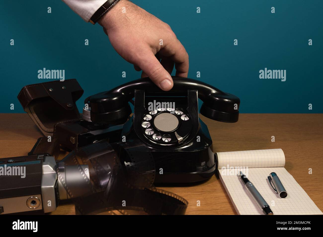 The hand reaches for the phone. Old telephone set on a wooden table, film camera Stock Photo