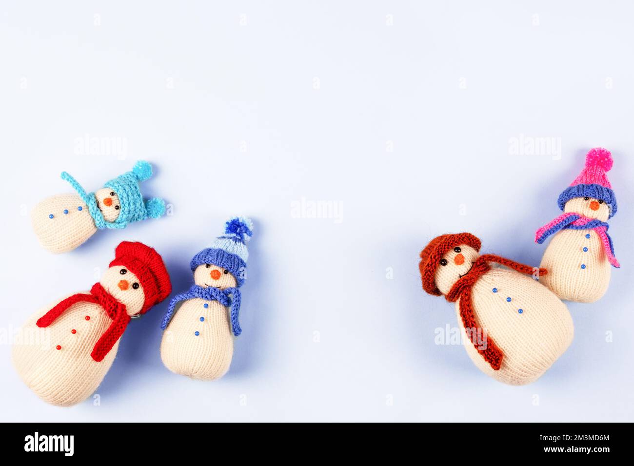 Knitted snowmen in colorful hats and scarves on a blue background. The ...