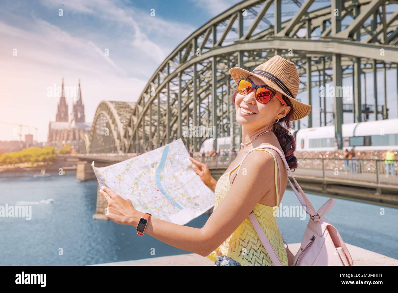 tourist girl with map, searching for landmarks and sights in old European city with bridge over Rhine river and Cologne cathedral in the background Stock Photo