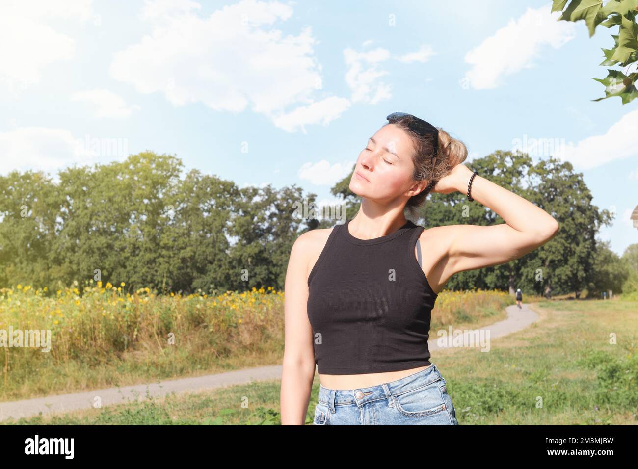 Young woman in summer park enjoying nature and bright sun Stock Photo